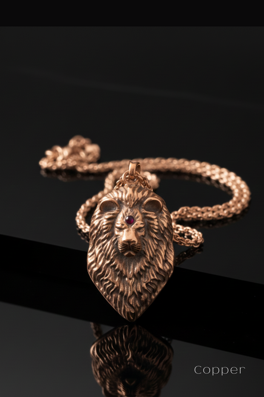 A close-up image of a gold-colored pendant with a lion's head design, resting on a reflective surface.