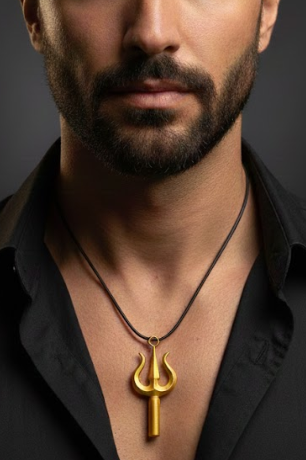 A close-up of a man's neck and chest area, with a gold-colored pendant necklace featuring a trident-like design hanging around his neck.