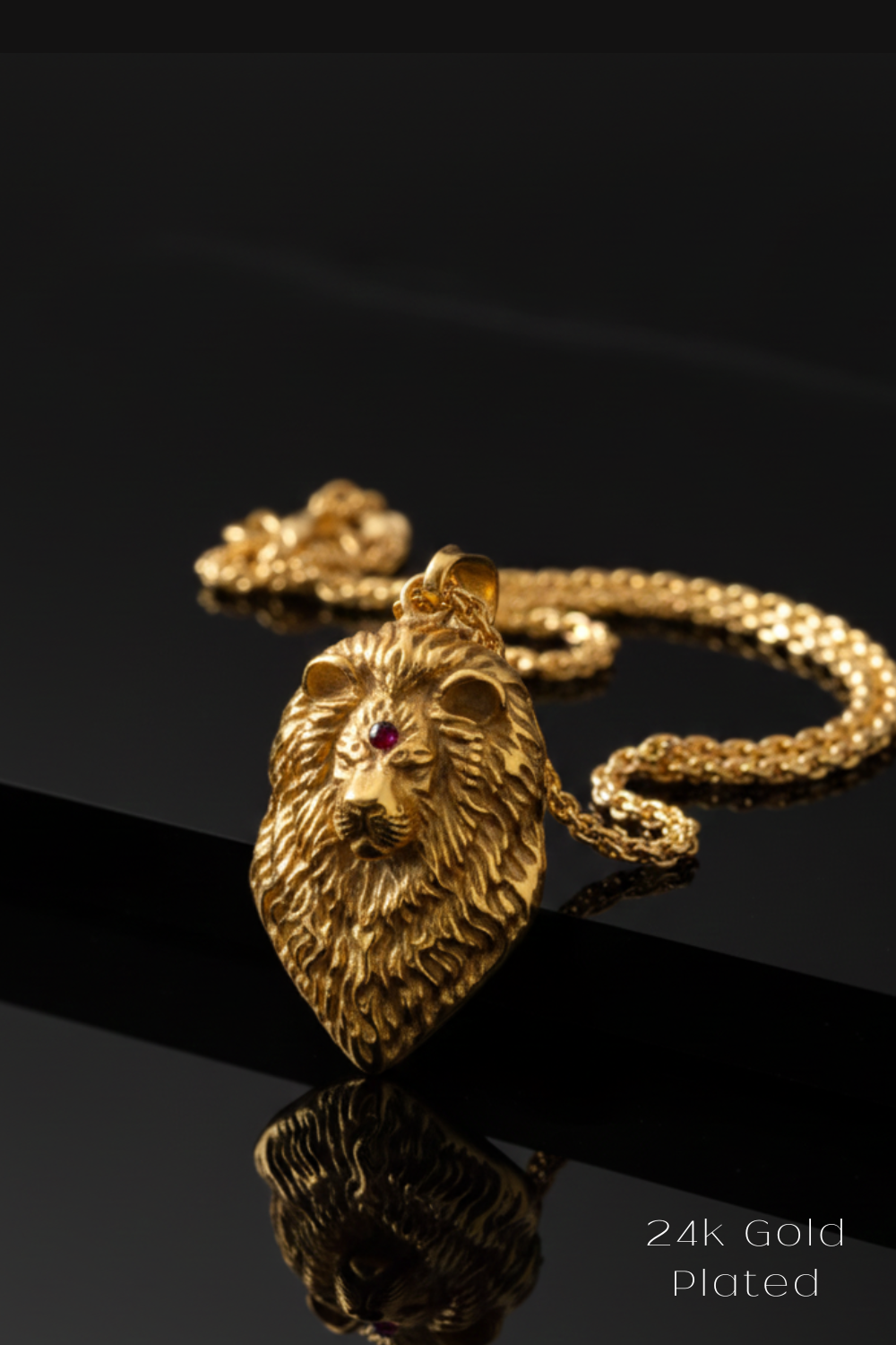 A close-up image of a gold-plated pendant in the shape of a lion's head, with a chain necklace visible in the background.