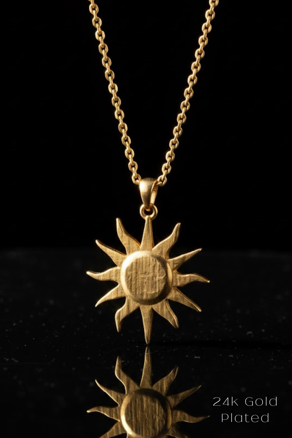 A gold-colored pendant necklace with a sun-shaped pendant is displayed against a black background.