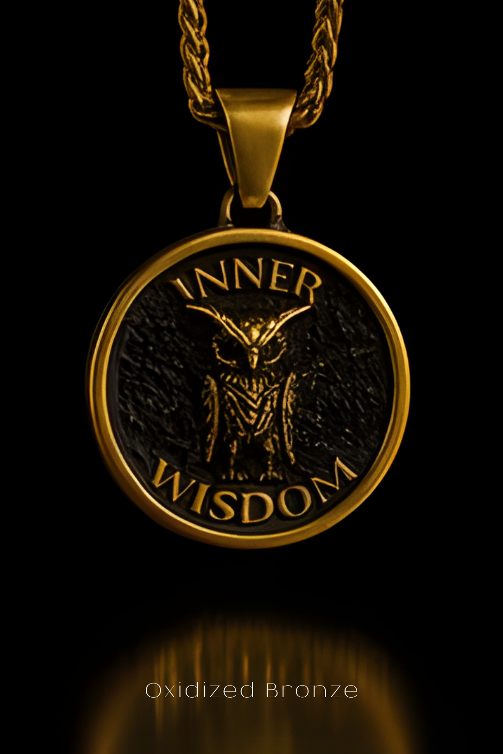 A gold-colored pendant with a black owl design and the words "INNER WISDOM" engraved on it, suspended from a chain against a black background.