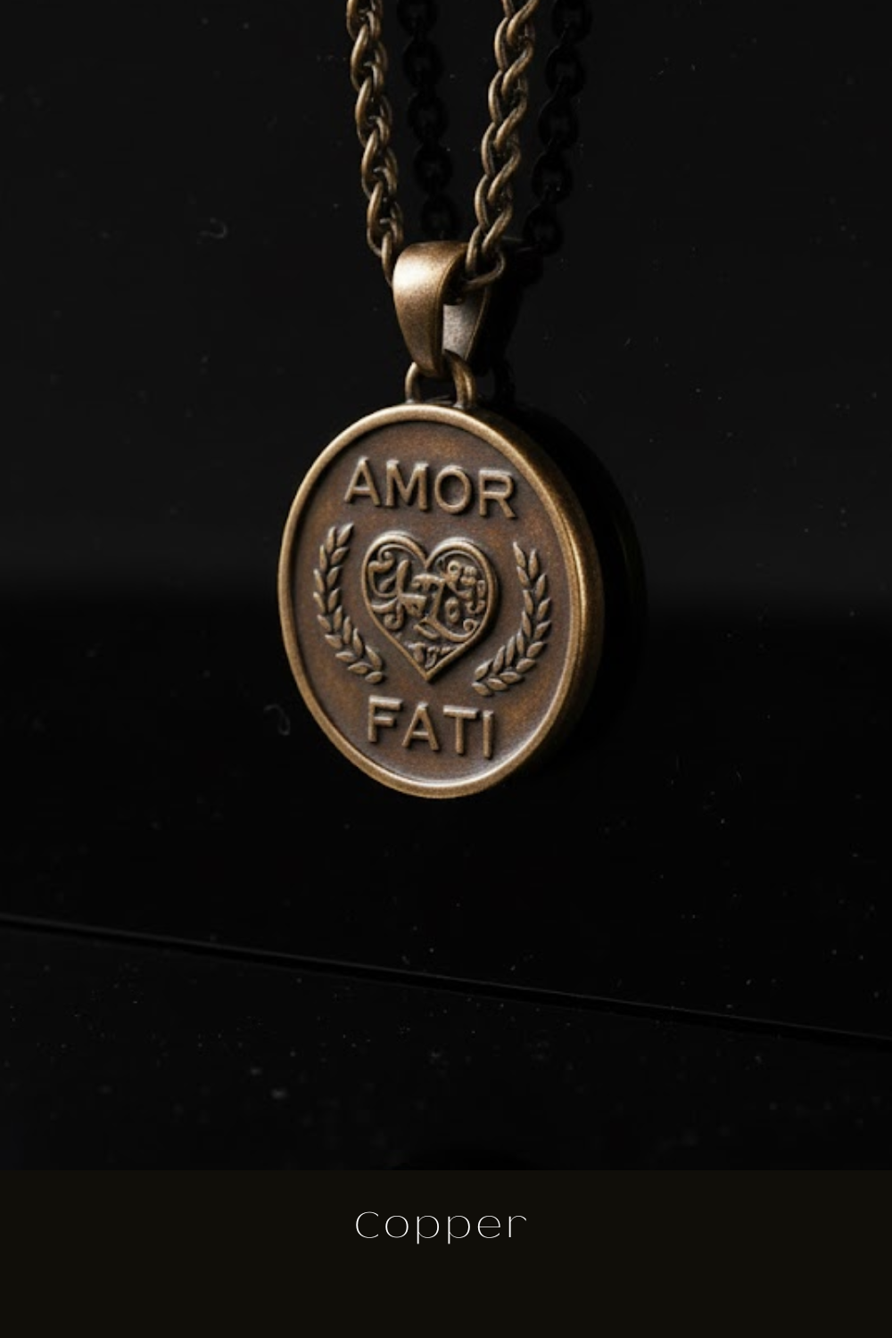 A close-up image of a bronze pendant necklace with the words "AMOR FAMI" engraved on it, hanging against a black background.