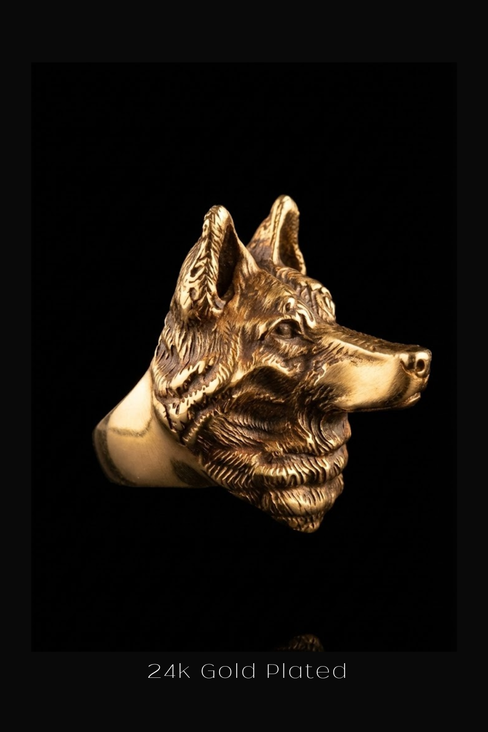 A close-up view of a gold-plated ring in the shape of a wolf's head against a black background.
