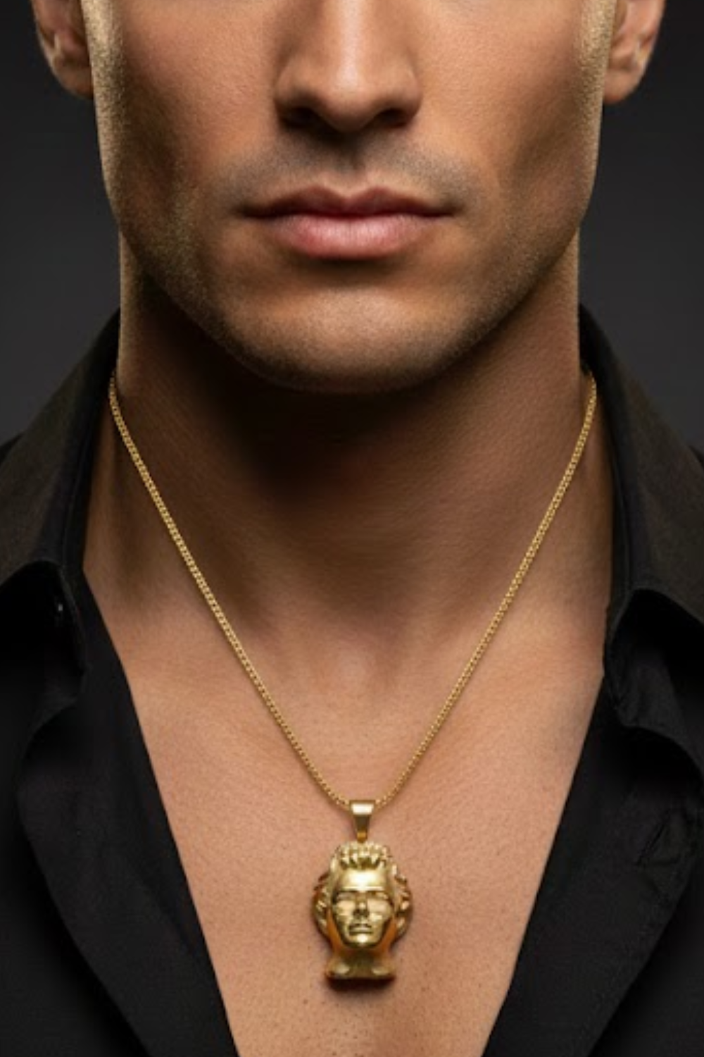 A close-up of a man's neck and chest area, with a gold-colored pendant featuring a human head design hanging from a chain around his neck.