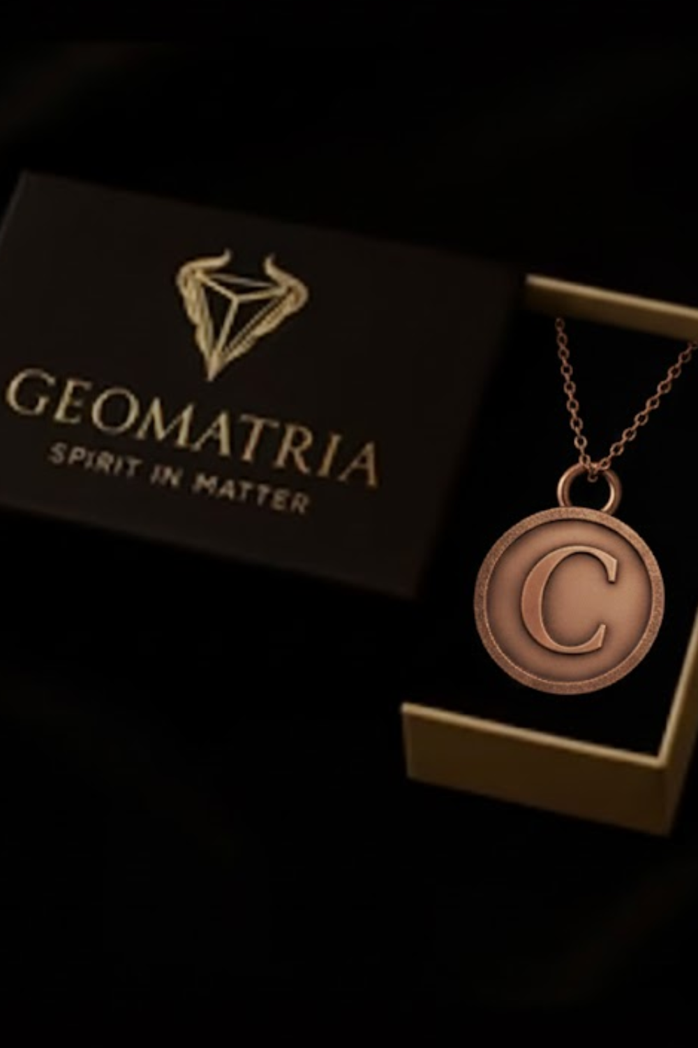 a necklace with a large letter 'C' pendant, displayed in a dark box with a gold-colored logo.