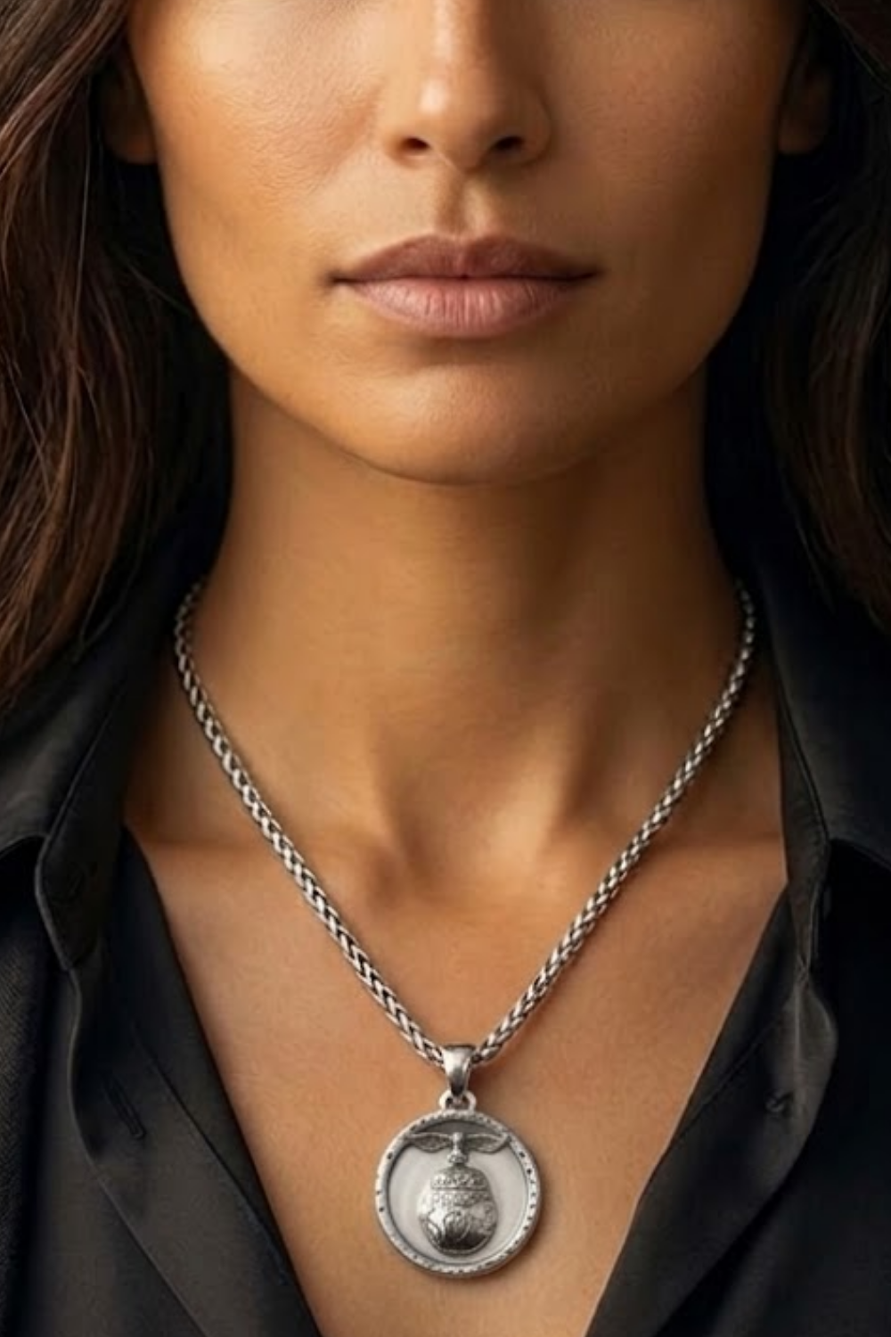 A close-up of a woman's neck and chest area, with a silver necklace featuring a pendant.