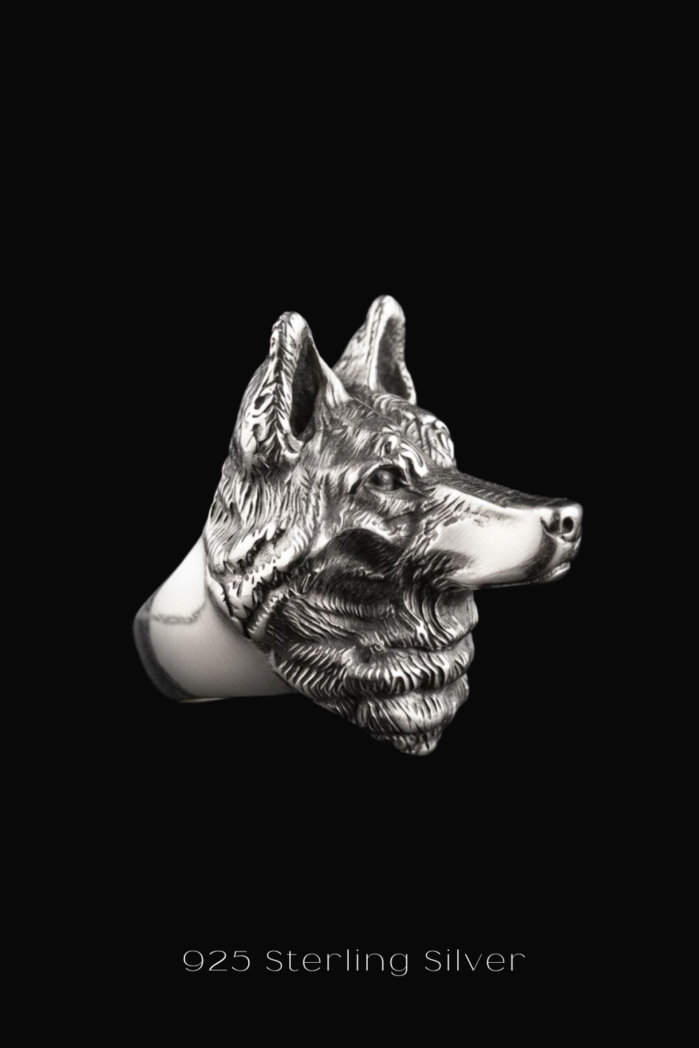 A close-up of a silver wolf head ring against a black background.