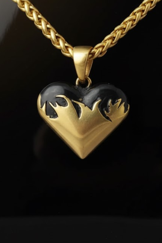 A gold-colored heart-shaped pendant with black accents, hanging from a chain.