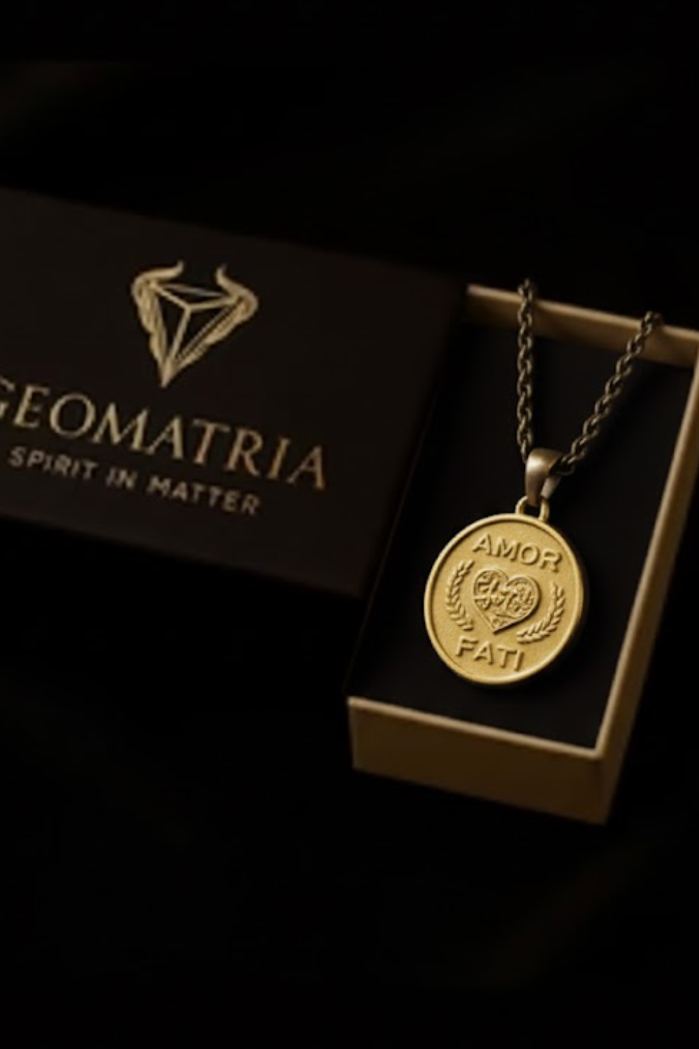 a gold-colored pendant necklace with a circular medallion attached to it, placed inside a black box with the word "Geomatria" printed on it.