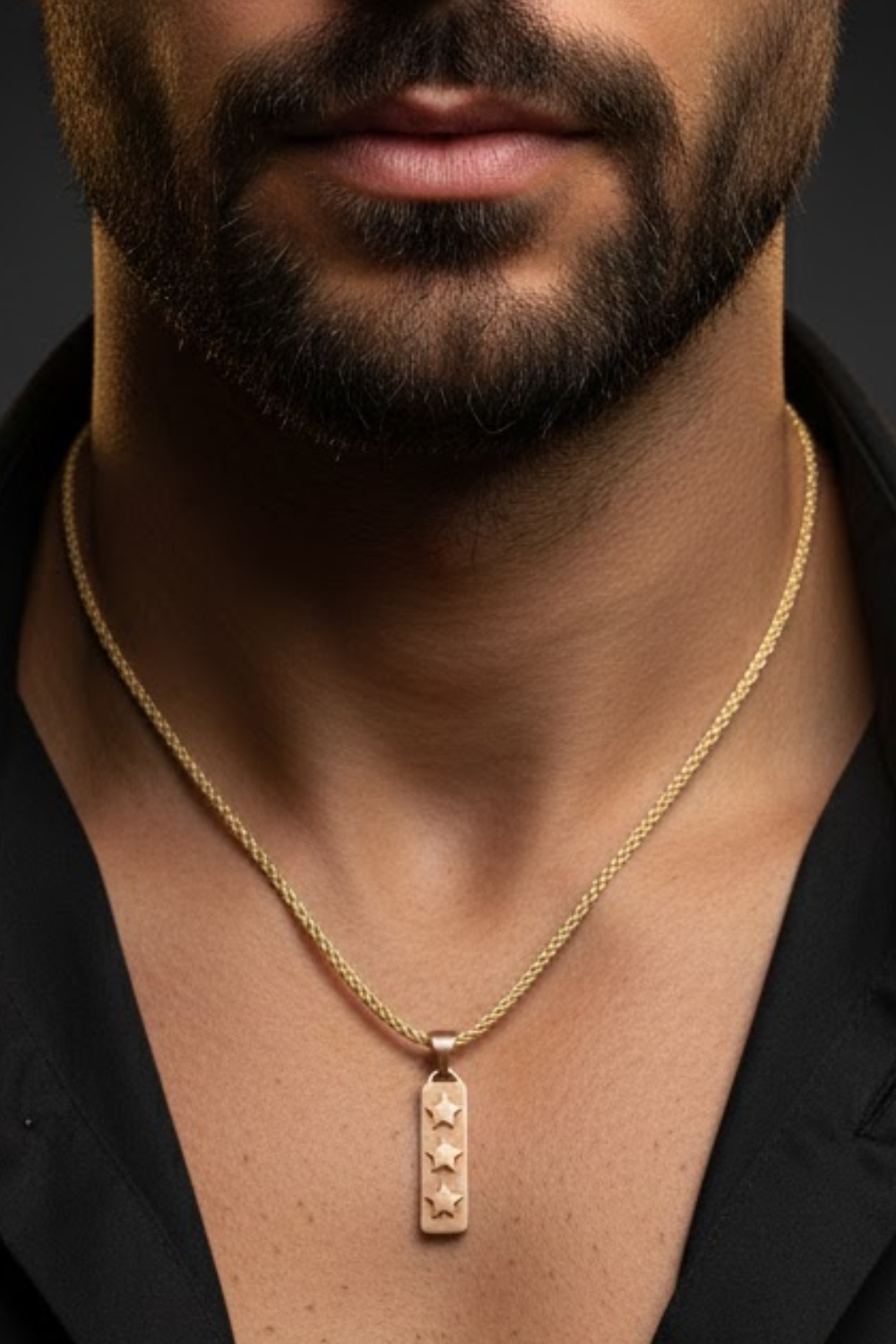 A close-up of a man's neck and chest area, with a gold necklace featuring a pendant with three stars.