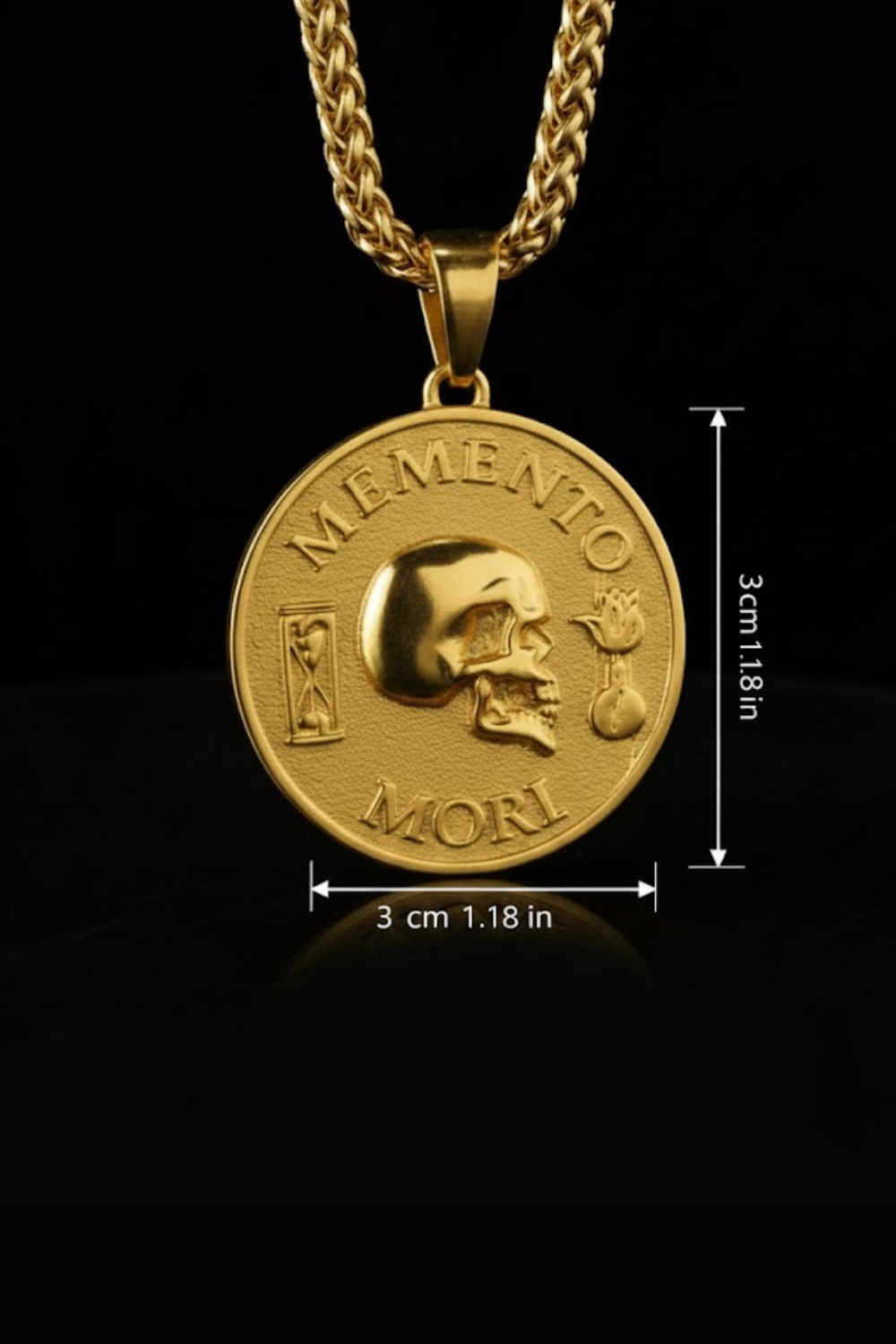 a gold-colored pendant necklace with a large circular medallion that has the Latin motto "MEMENTO MORI" engraved on it. The pendant is shown against a black background, and there are measurements provided to indicate its size.