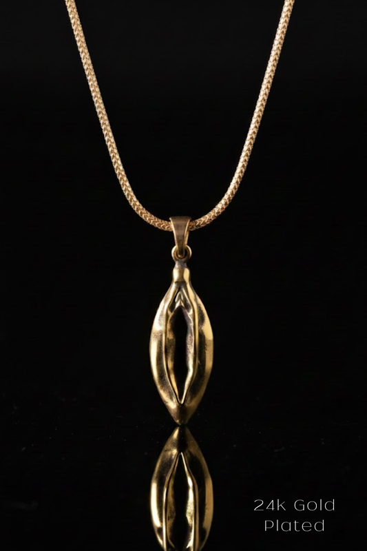 A gold-plated pendant necklace with a unique, sculpted design is displayed against a black background.