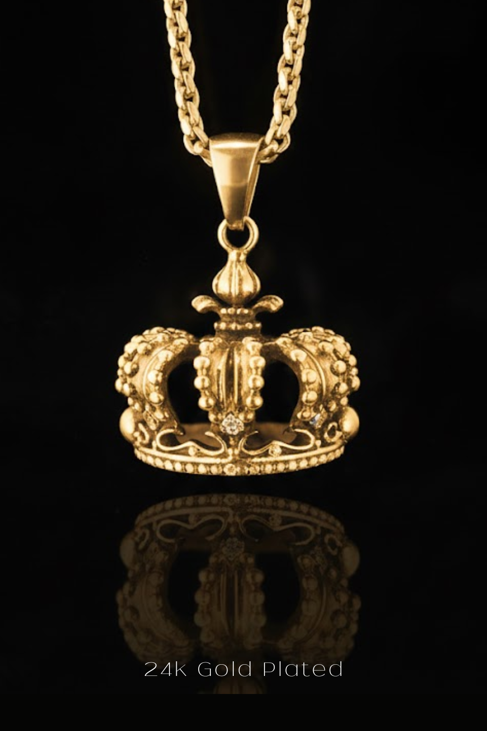 A 24k gold plated pendant in the shape of a crown is displayed against a black background.