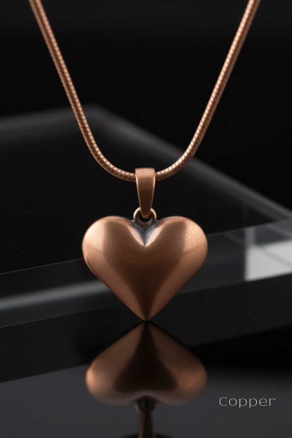 A copper-colored heart-shaped pendant necklace with a chain is displayed against a black background.
