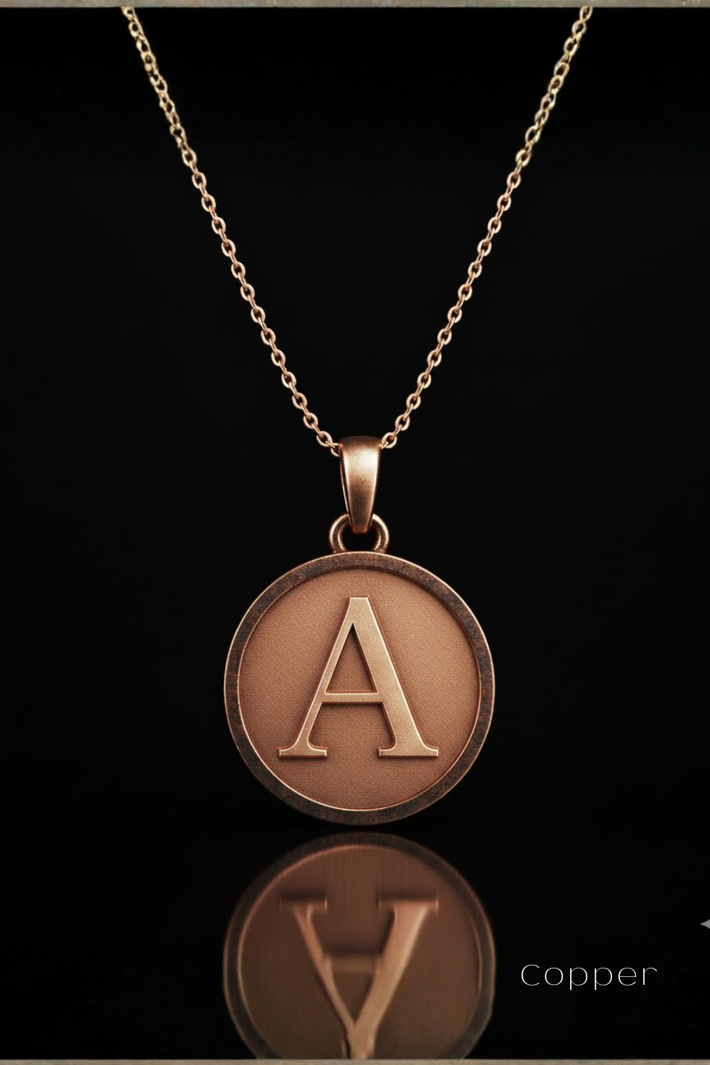 A gold-colored necklace with a large circular pendant featuring the letter "A" in the center.