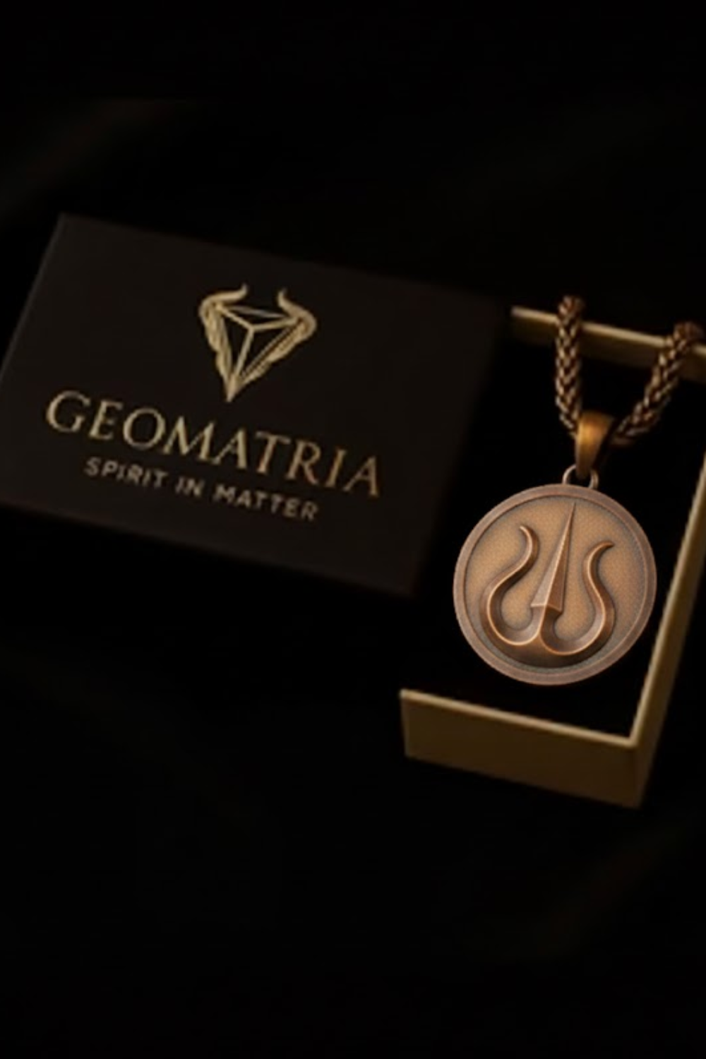 a pendant with a geometric design, displayed in a box with the text "Geomatria Spirit in Matter" written on it.