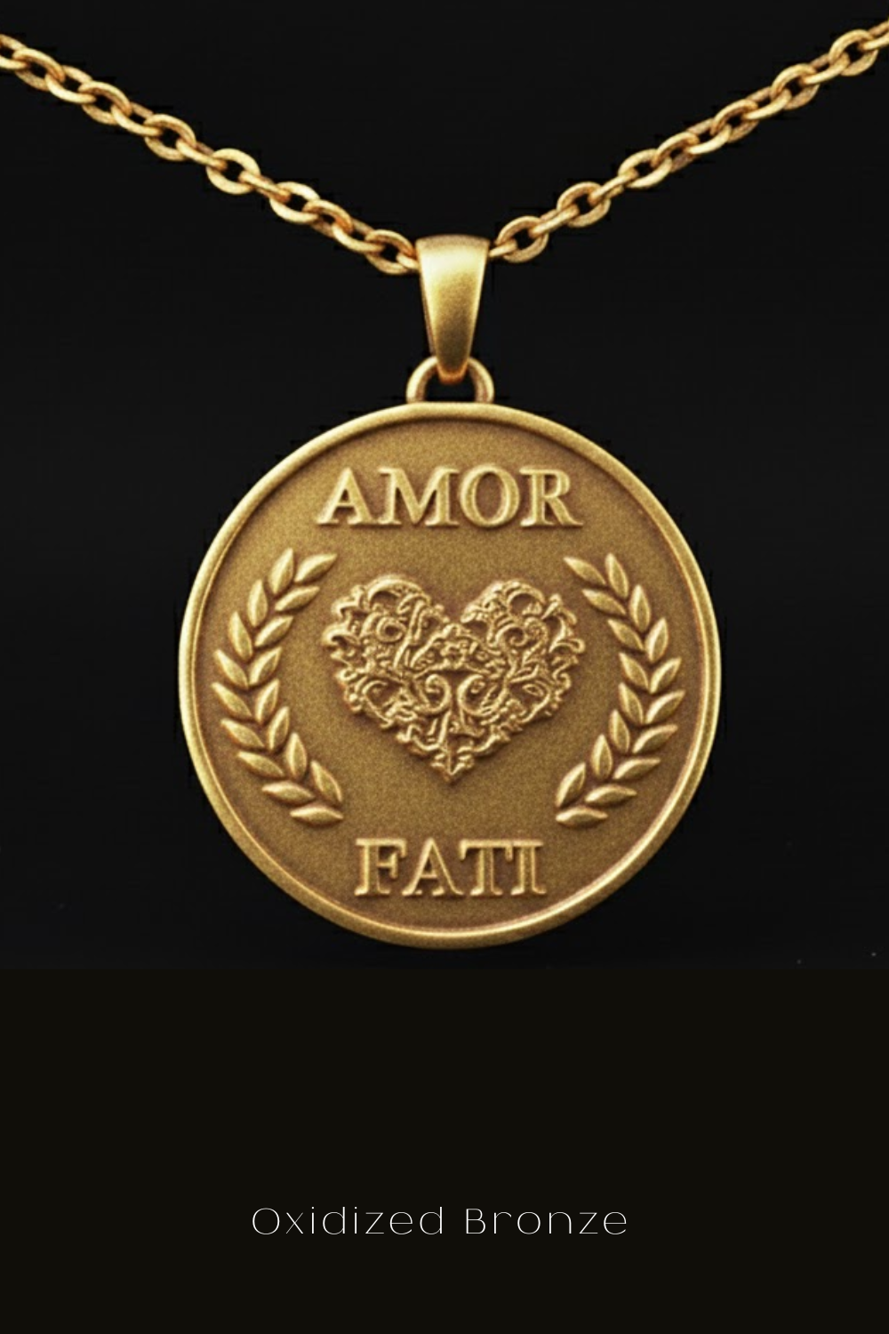 a close-up view of a gold-colored pendant with a heart-shaped design and the words "Amor Fati" engraved on it.