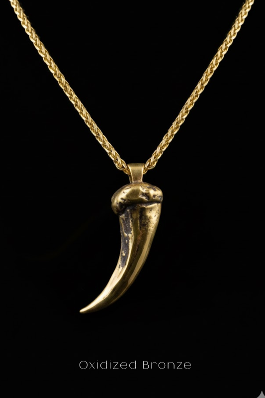 A close-up view of a gold-colored pendant with a sharp, pointed design, suspended from a chain against a black background.