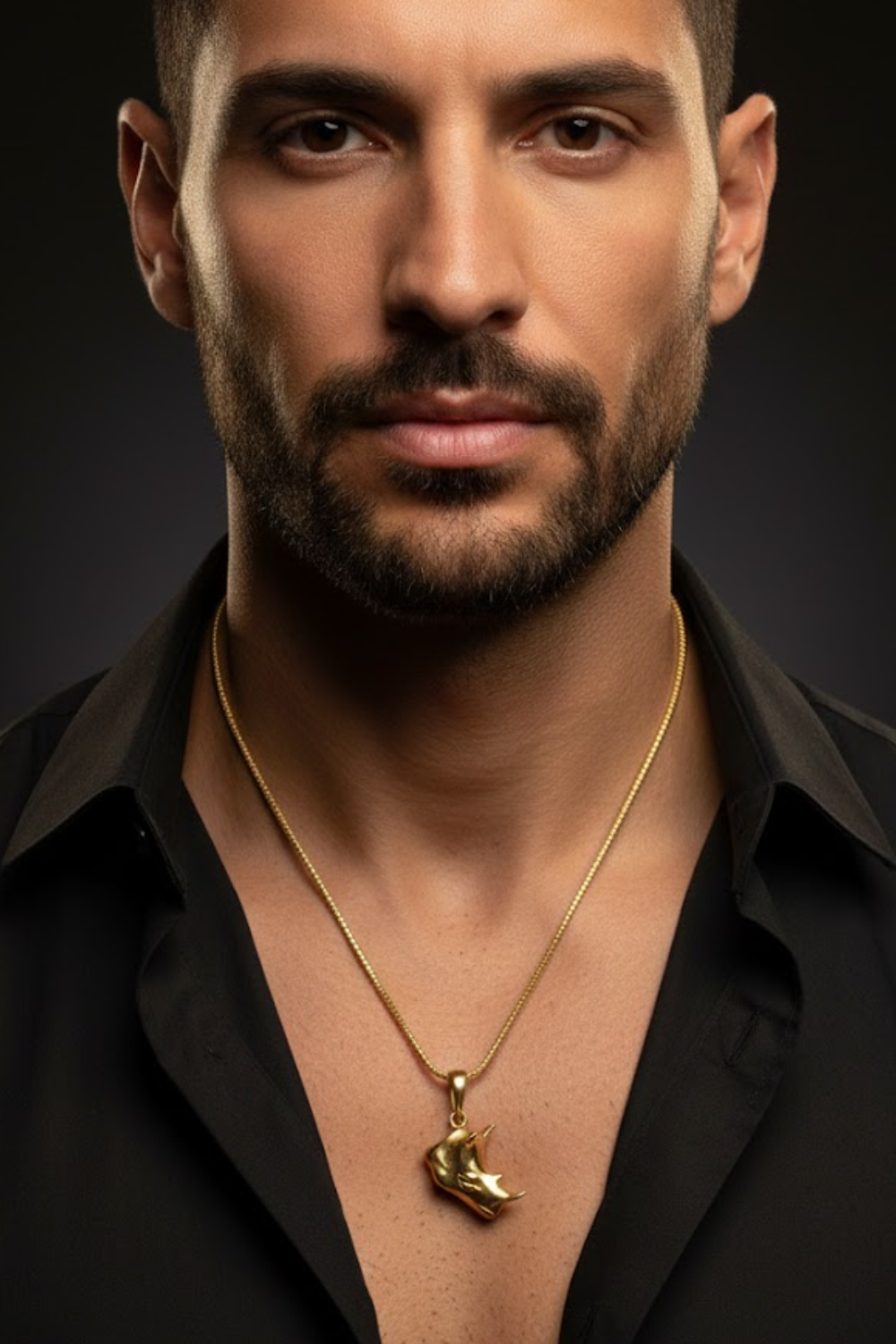 A man with a beard wearing a black shirt and a gold necklace with a pendant.