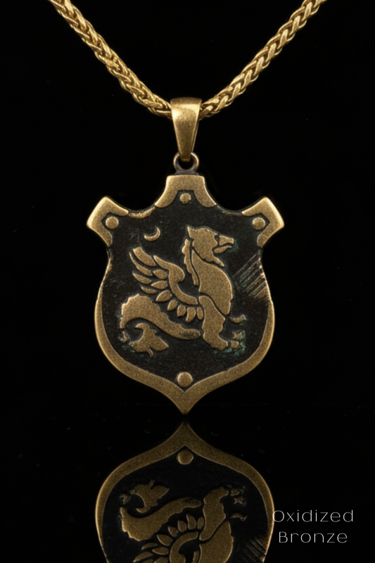 A gold-colored pendant necklace with a shield-shaped pendant featuring a winged creature, possibly a dragon or a mythical bird.