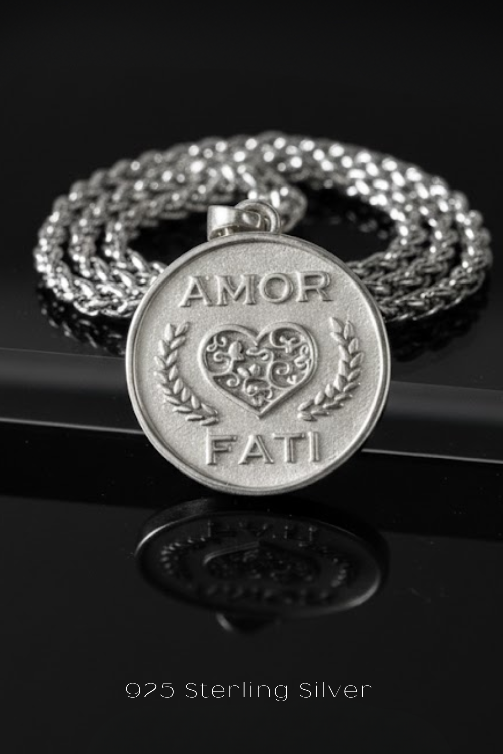 A silver pendant with the words "AMOR FAMI" engraved on it, surrounded by a silver chain.