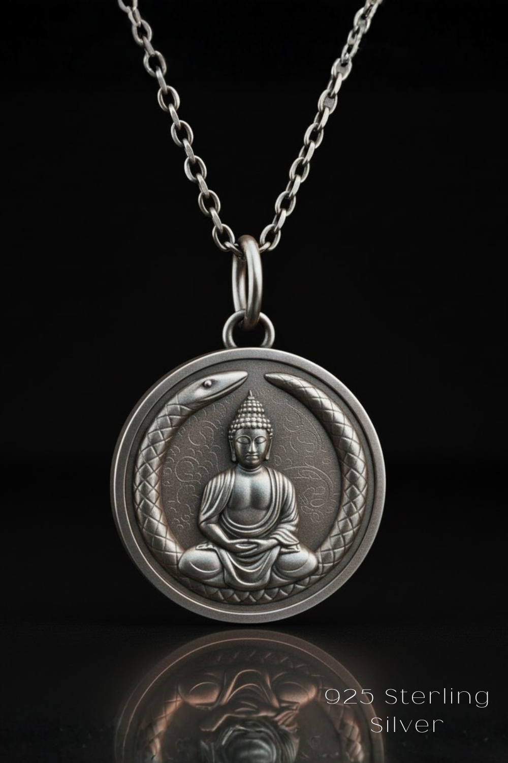 A silver-colored pendant necklace with a medallion featuring a Buddha figure sitting between two snakes.