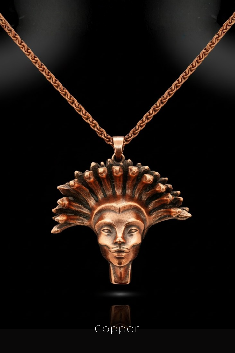 A copper-colored pendant necklace with a detailed, stylized face design.