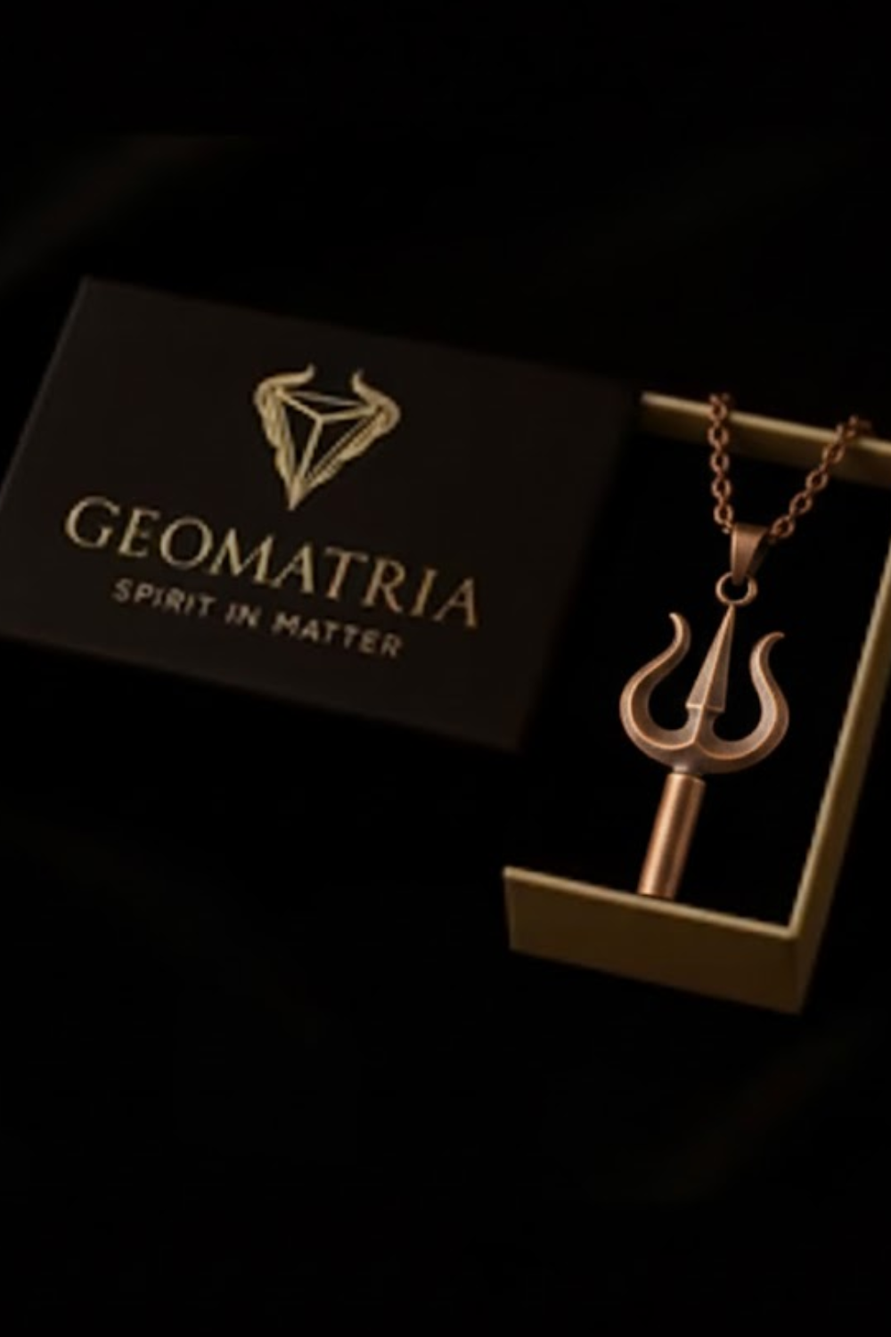 a necklace with a pendant, placed inside a black box with the word "Geomatria" written on it.