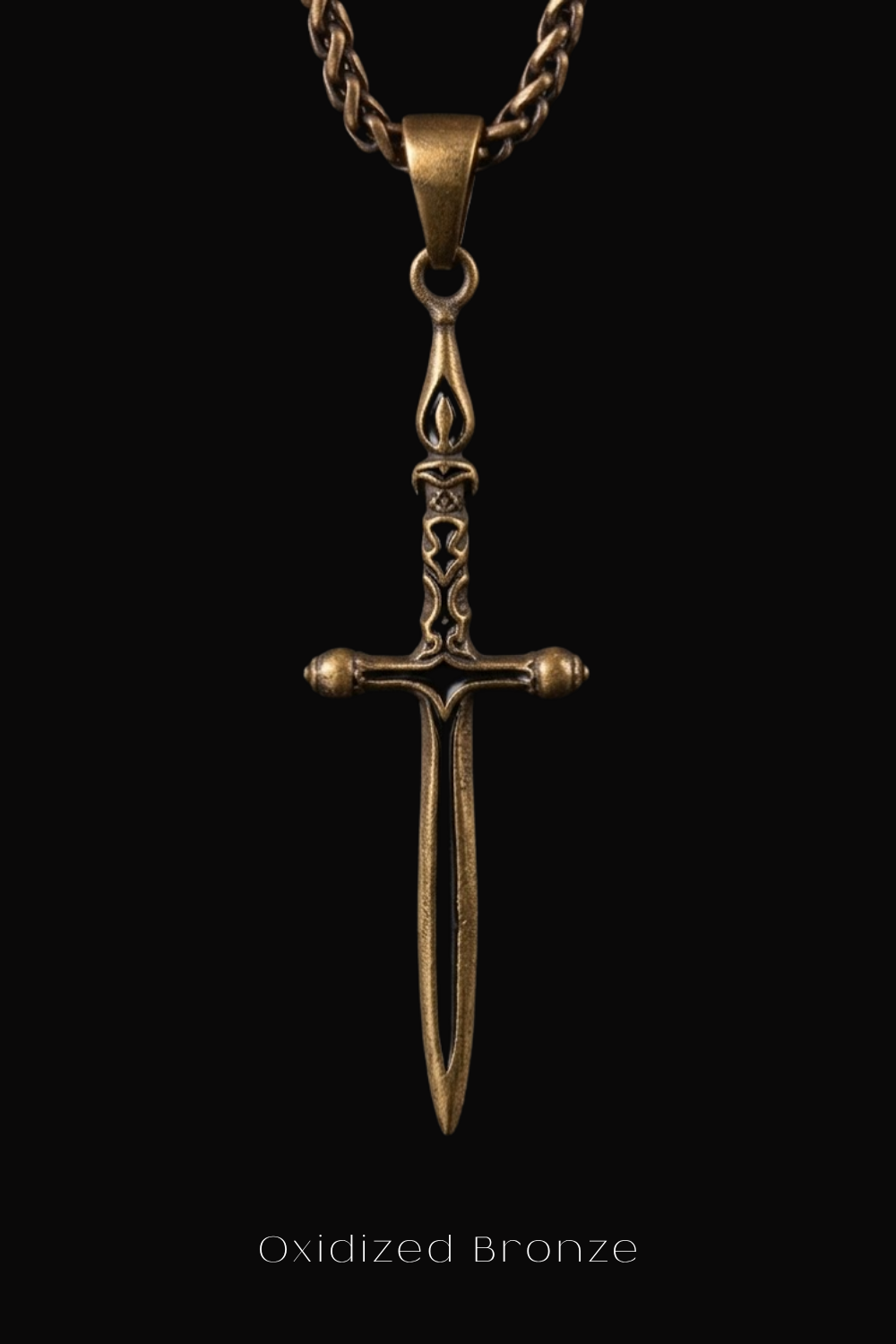 A close-up view of an oxidized bronze pendant in the shape of a sword against a black background.